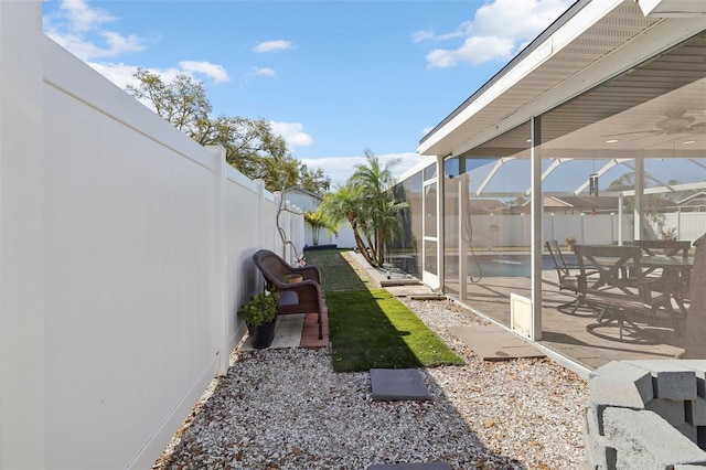 view of yard with glass enclosure, a patio area, a pool, and a fenced backyard