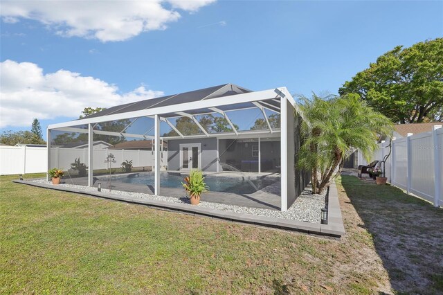 rear view of house featuring glass enclosure, a yard, french doors, and a fenced backyard