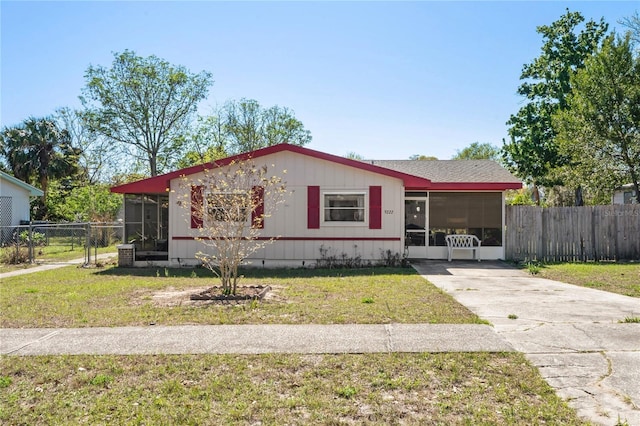 view of front of property with a front lawn, fence, driveway, and a sunroom