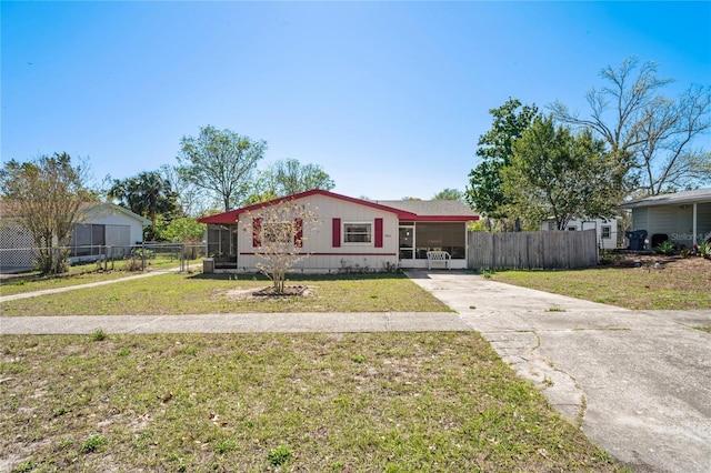 view of front of house with concrete driveway, fence, and a front yard