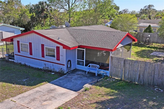 view of front of property with a front yard, fence, driveway, roof with shingles, and a patio area