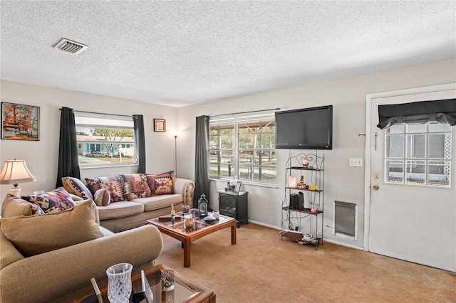 living room featuring visible vents, light colored carpet, and a textured ceiling