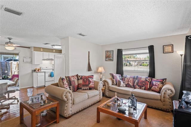 living area with visible vents, a textured ceiling, light wood-style floors, and ceiling fan