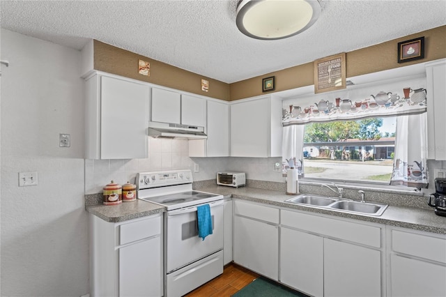 kitchen with under cabinet range hood, electric range, white cabinets, and a sink