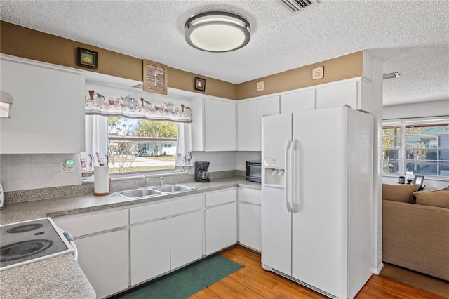 kitchen featuring light countertops, light wood-style floors, white appliances, white cabinetry, and a sink