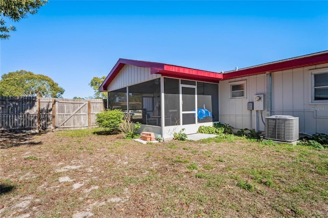 rear view of house with cooling unit, a sunroom, and fence