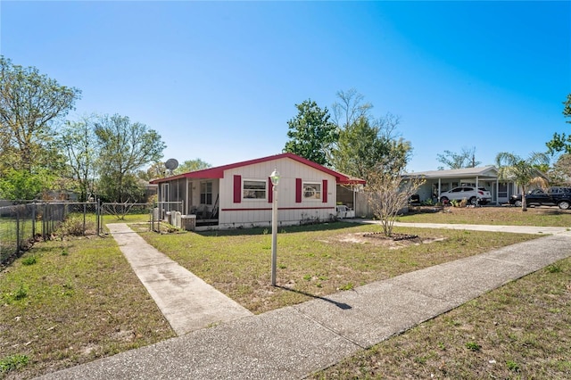 view of front of home featuring a front yard, a gate, fence, driveway, and a sunroom