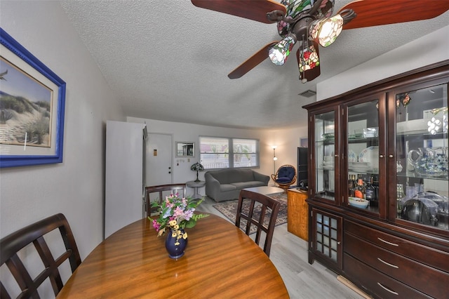 dining area with wood finished floors, a ceiling fan, and a textured ceiling