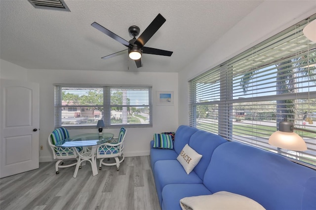 living room with visible vents, baseboards, ceiling fan, wood finished floors, and a textured ceiling