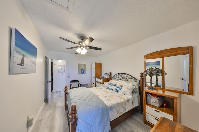 bedroom featuring ceiling fan, baseboards, a textured ceiling, and wood finished floors