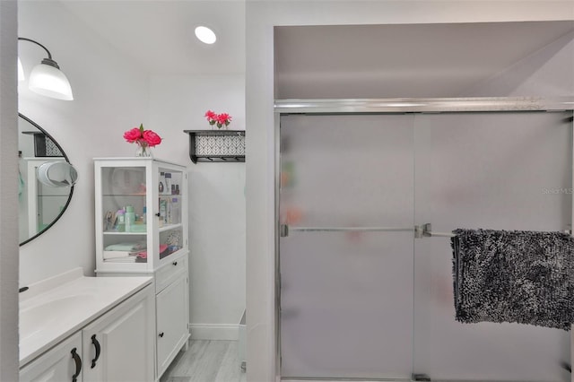 full bathroom featuring baseboards, vanity, wood finished floors, and a shower stall