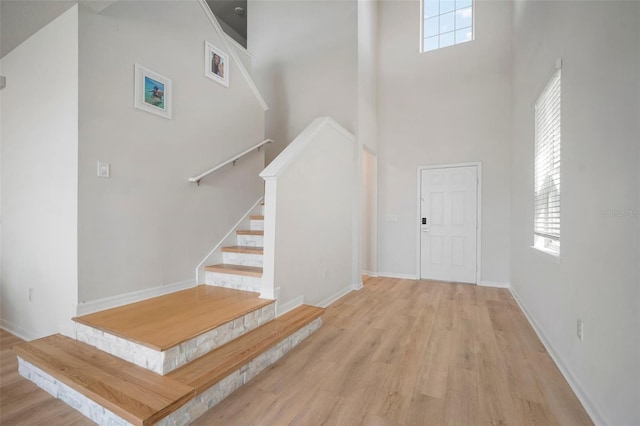 foyer entrance featuring stairs, a high ceiling, wood finished floors, and baseboards