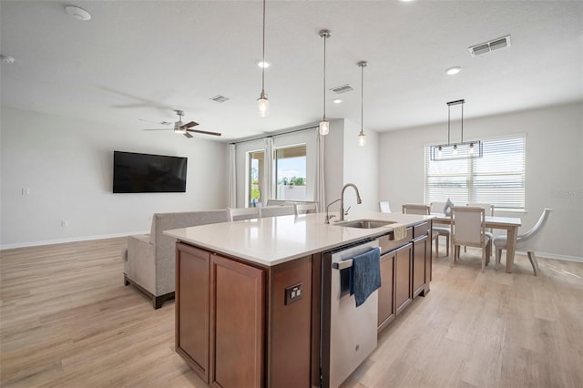 kitchen featuring dishwasher, a kitchen island with sink, visible vents, and a sink