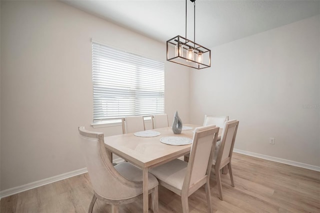 dining space with baseboards, a notable chandelier, and light wood-style flooring