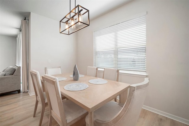 dining area with baseboards, light wood-style floors, and an inviting chandelier