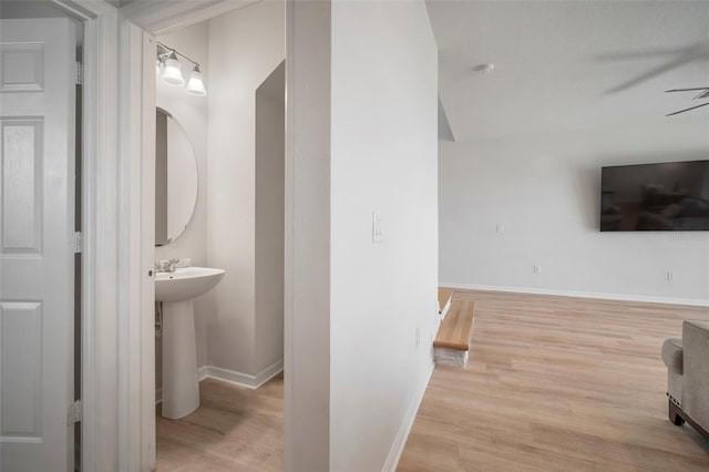 bathroom featuring a sink, ceiling fan, baseboards, and wood finished floors