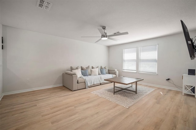 living room with a ceiling fan, visible vents, light wood finished floors, and baseboards