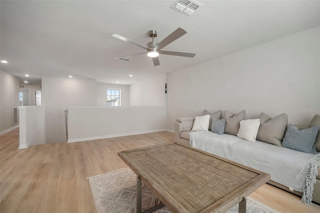 living room with visible vents, baseboards, light wood-style flooring, and a ceiling fan