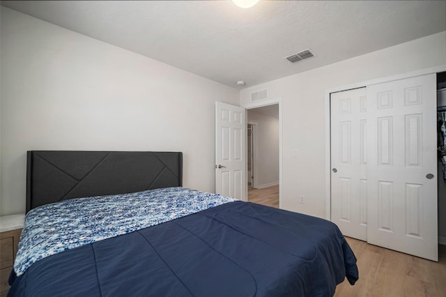 bedroom featuring a closet, visible vents, and light wood finished floors