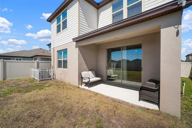 rear view of property featuring a patio area, fence, a lawn, and stucco siding