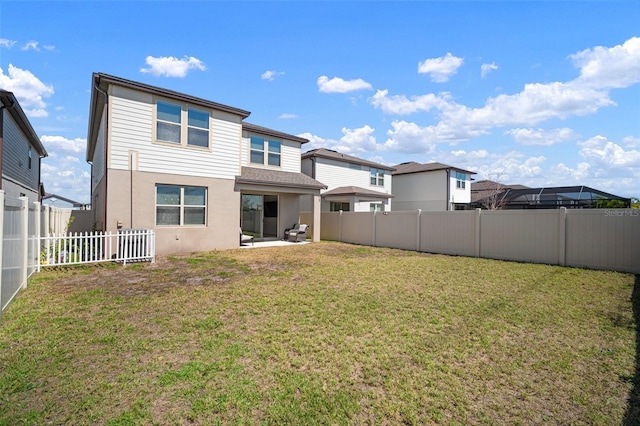 rear view of house featuring a yard, a fenced backyard, stucco siding, and a patio area