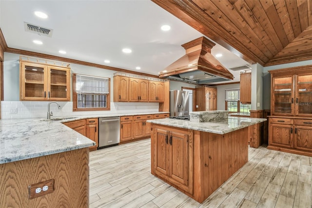 kitchen featuring visible vents, a sink, appliances with stainless steel finishes, island range hood, and vaulted ceiling