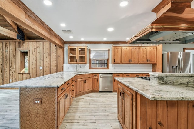 kitchen featuring visible vents, a sink, appliances with stainless steel finishes, a peninsula, and light stone countertops