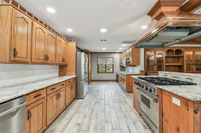 kitchen featuring visible vents, light wood-style flooring, appliances with stainless steel finishes, decorative backsplash, and light stone countertops