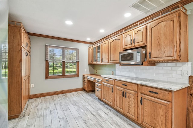 kitchen featuring tasteful backsplash, stainless steel microwave, light wood finished floors, visible vents, and baseboards