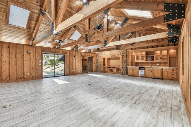 unfurnished living room featuring beam ceiling, wood walls, a skylight, and wood ceiling