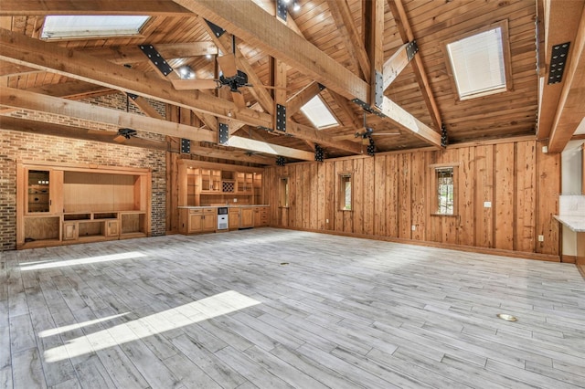 unfurnished living room with wooden ceiling, a skylight, and wooden walls
