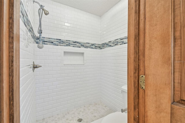 bathroom with toilet, a shower stall, and a textured ceiling