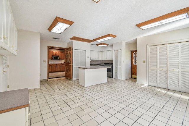 kitchen featuring dark countertops, visible vents, a kitchen island, white cabinets, and stainless steel appliances