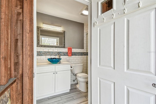 bathroom featuring wainscoting, vanity, toilet, and tile walls