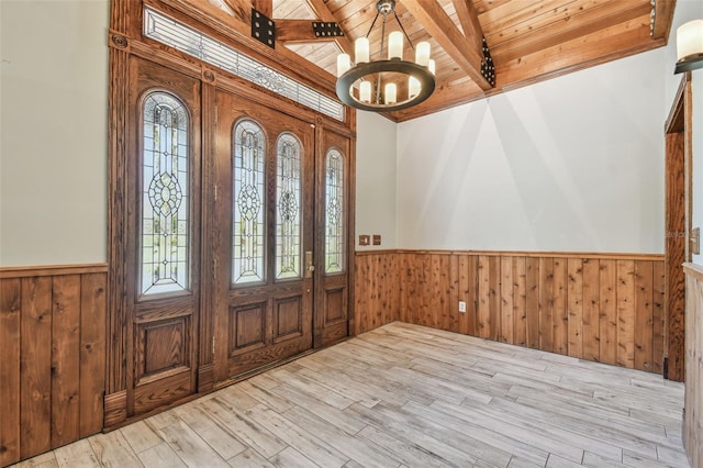 entrance foyer with a chandelier, a wainscoted wall, wooden ceiling, and beam ceiling