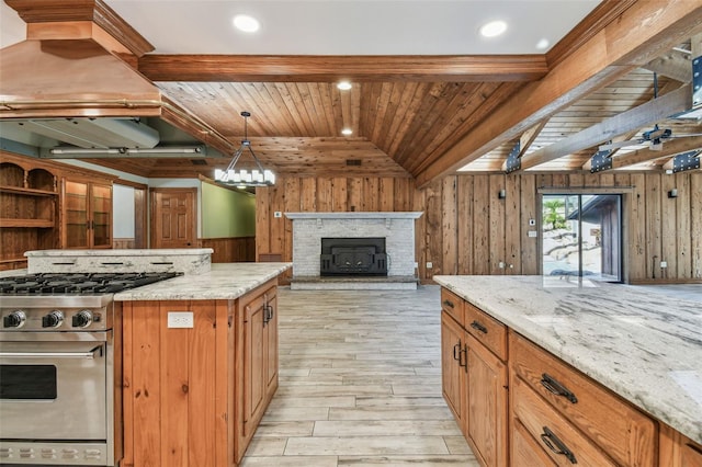 kitchen with vaulted ceiling with beams, light stone countertops, wood walls, wood ceiling, and stainless steel range