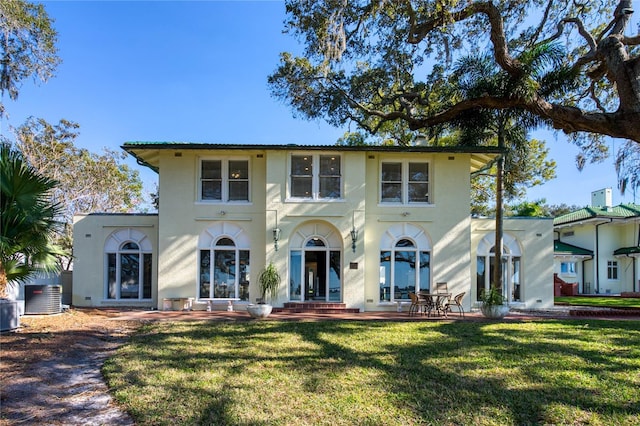 mediterranean / spanish house with a front lawn, central AC unit, and stucco siding