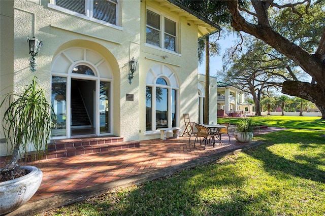 doorway to property featuring stucco siding and a lawn