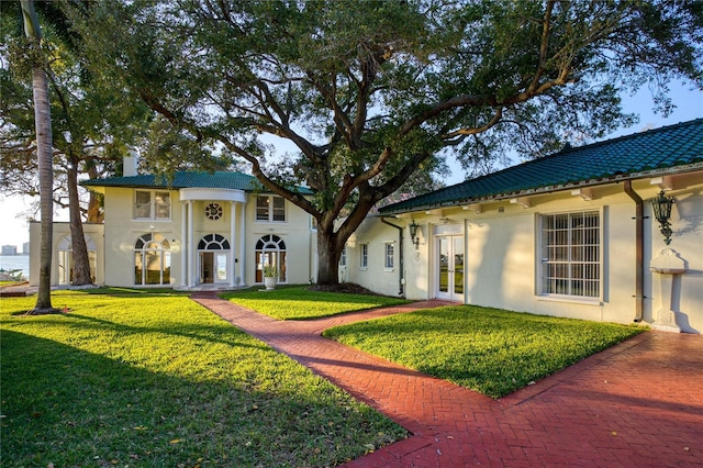 exterior space featuring a front yard, french doors, a tile roof, and stucco siding