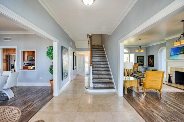 entrance foyer featuring visible vents, stairway, crown molding, and light wood-style floors