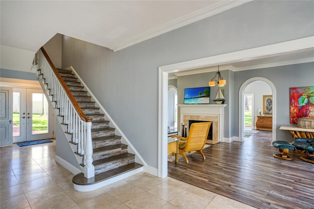 stairway with arched walkways, french doors, baseboards, and ornamental molding