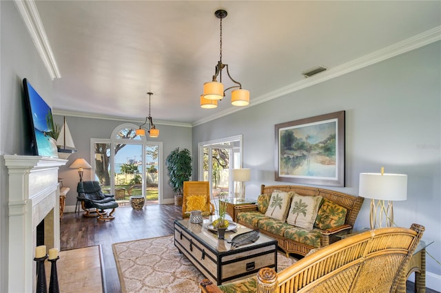 living area with visible vents, baseboards, a fireplace with flush hearth, ornamental molding, and wood finished floors