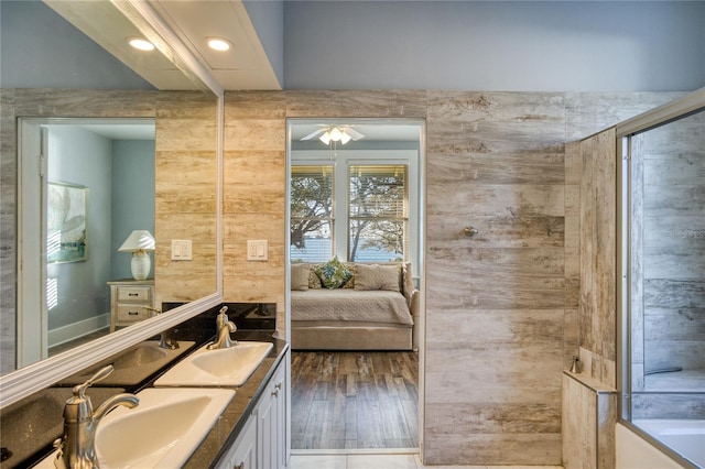 full bath featuring a ceiling fan, wood finished floors, ensuite bath, double vanity, and a sink