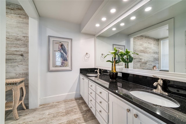 bathroom with a sink, baseboards, wood finished floors, and double vanity