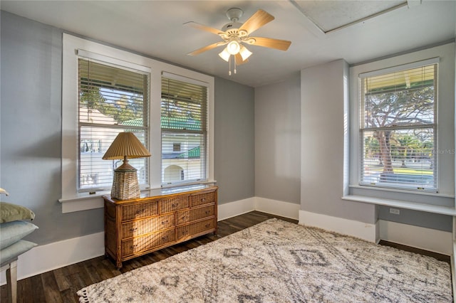 interior space featuring baseboards, plenty of natural light, dark wood-type flooring, and a ceiling fan