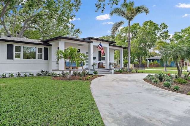 view of front of home featuring a porch, curved driveway, stucco siding, and a front lawn
