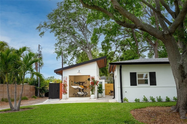 rear view of house with stucco siding, fence, and a yard