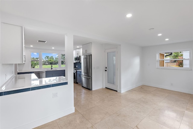 kitchen with a sink, appliances with stainless steel finishes, a wealth of natural light, and visible vents