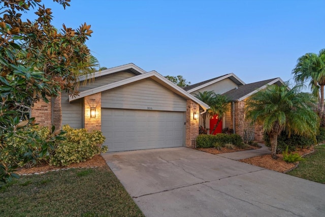 view of front of home featuring a garage, brick siding, and driveway