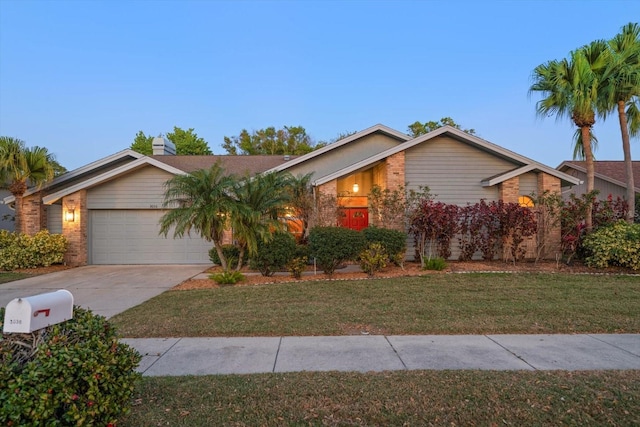 mid-century inspired home with brick siding, a garage, a front yard, and driveway